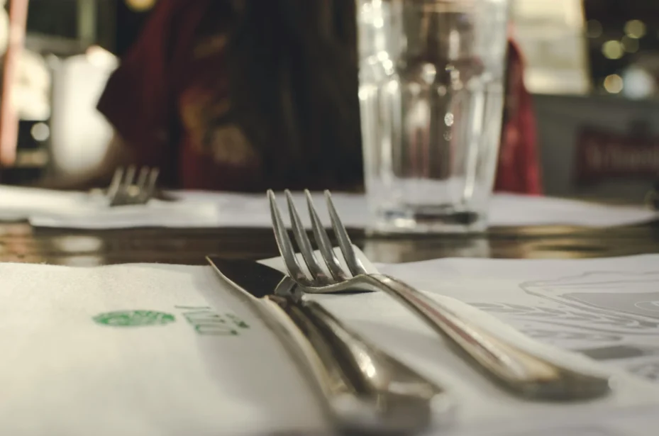 A fork and a knife on a placemat on a table.